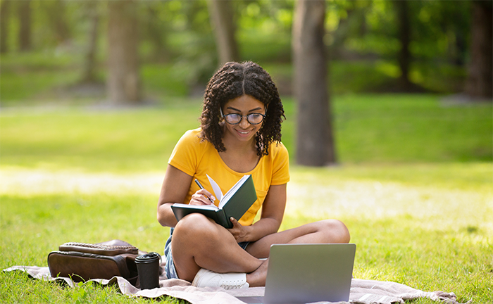 A student taking notes outside on her notebook